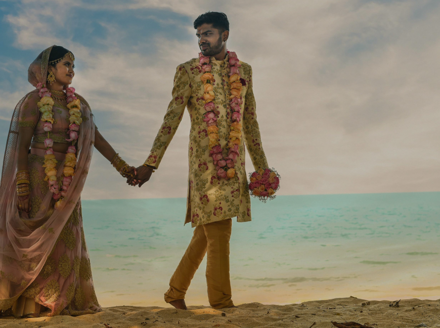 Couple walking on the beach with their wedding attire