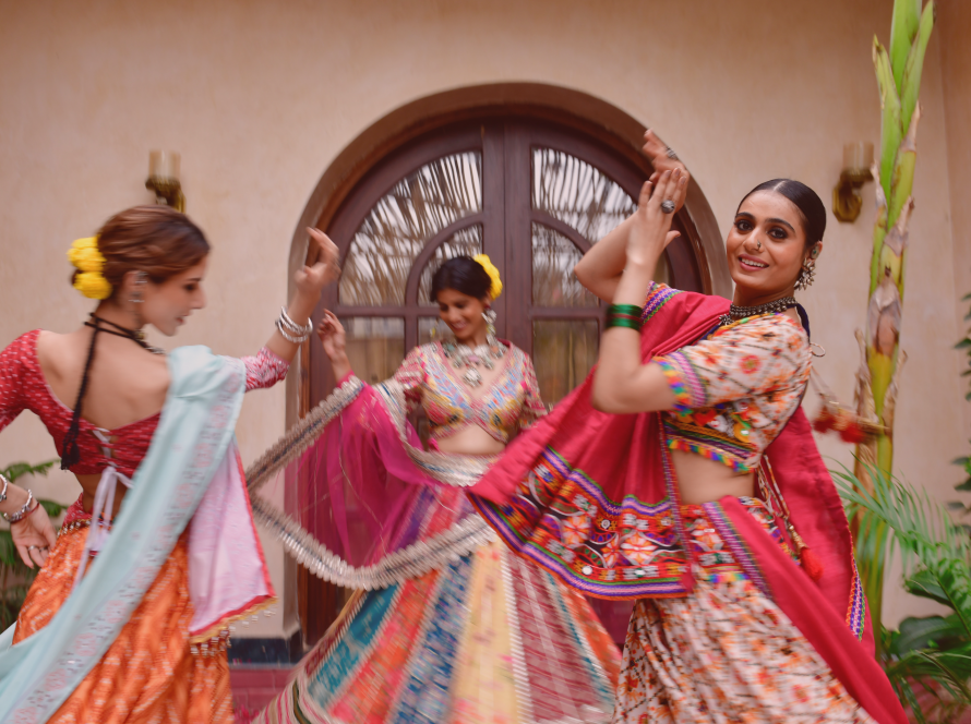 Photo of three young women dong garba indoors.