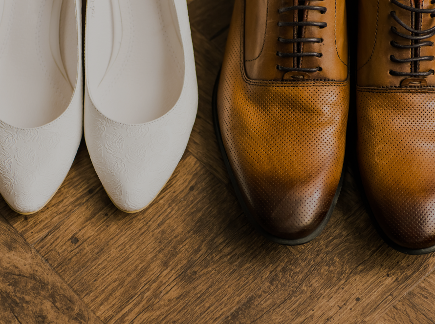 Groom's shoe next to bride's sandals