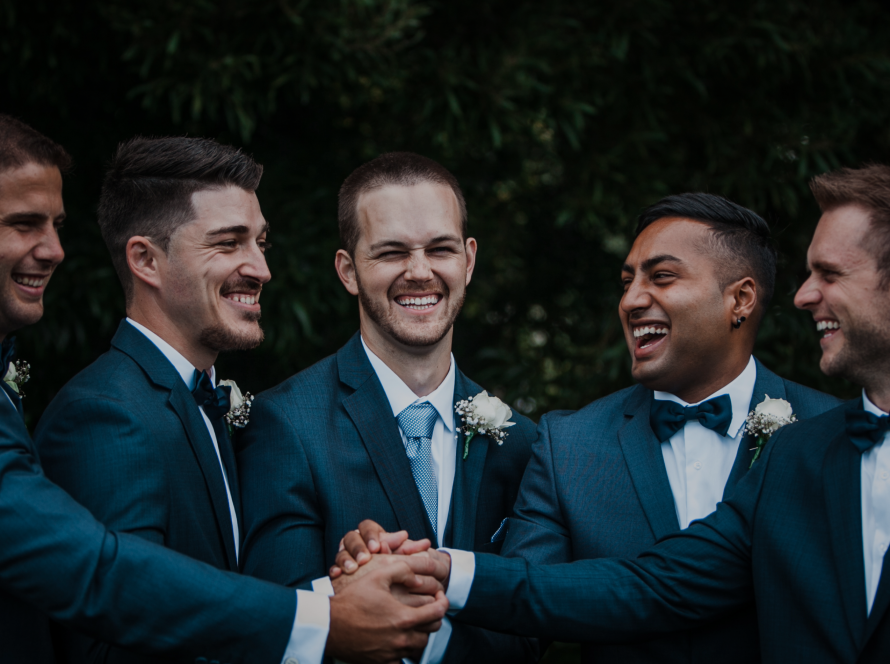 4 groomsmen standing next to the groom. The groom being in the center